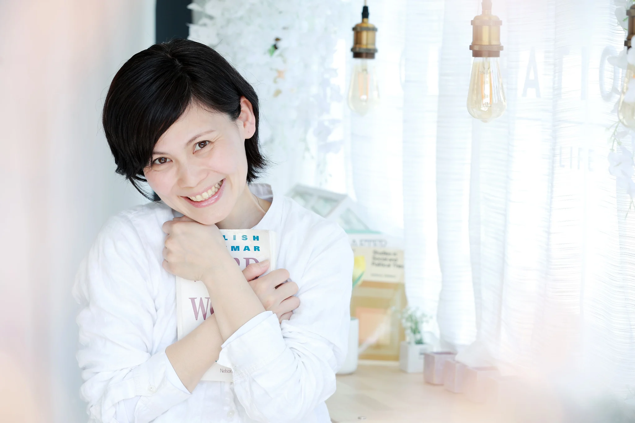 本を手に微笑む、片づけコンサルタントの矢川朱美